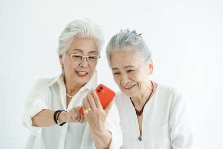Senior women looking at smartphone screens with a smileの写真素材