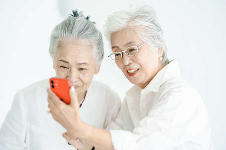 Senior women looking at smartphone screens with a smileの写真素材