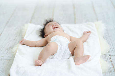 Baby crying in a diaper on the floorの写真素材