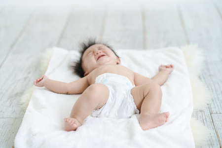 Baby crying in a diaper on the floorの写真素材
