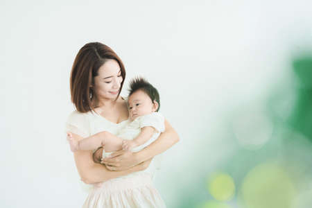 Asian mom holding a baby in the bright roomの写真素材