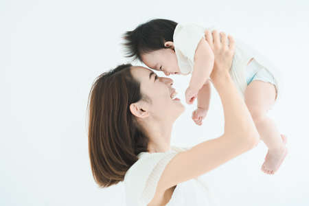 Mom holding the baby high in the bright roomの写真素材