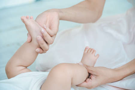 Mother's hands supporting the baby's feet in the roomの写真素材