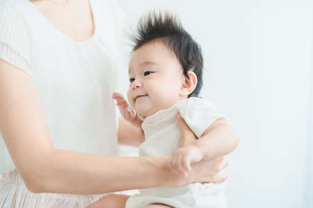 Asian baby to be hugged in a bright roomの写真素材