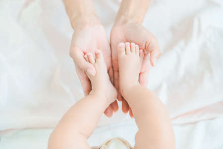 Mother's hands supporting the baby's feet in the roomの写真素材