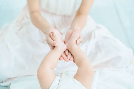 Mother's hands supporting the baby's feet in the roomの写真素材