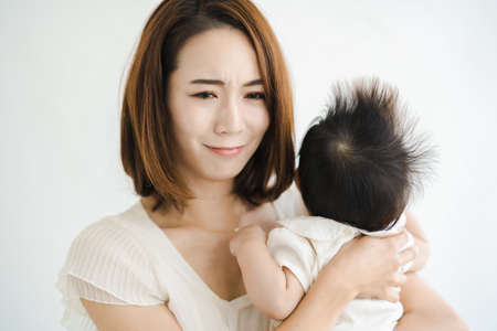 Asian mother holding a baby and looking tired