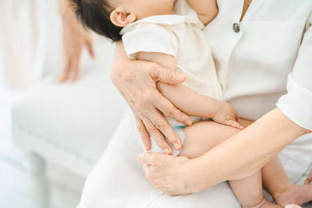 Senior women hugging and interacting with baby in the roomの写真素材