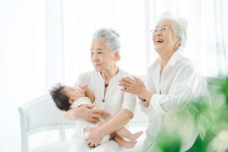 Senior women hugging newborn baby in the roomの写真素材