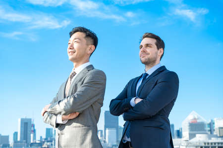Asian / European businessmen, city and blue skyの写真素材