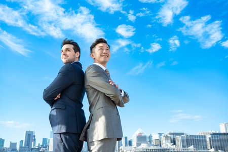 Asian / European businessmen, city and blue skyの写真素材