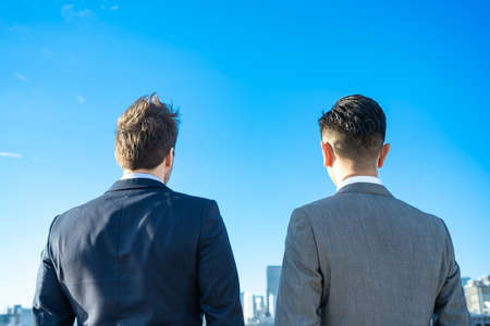 Two business men stands on fine dayの写真素材