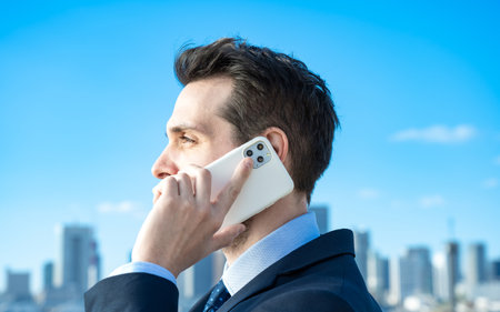 A businessman talking on a smartphone on fine dayの写真素材