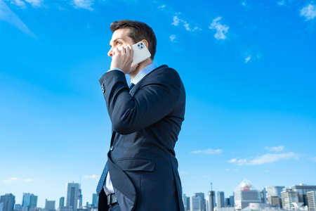 A businessman talking on a smartphone on fine dayの写真素材