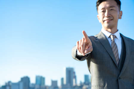 A businessman posing with his index finger up on fine dayの写真素材