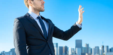 A businessman against the backdrop of the blue sky and buildingsの写真素材
