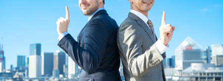 two businessmen posing under the blue skyの写真素材