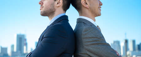 two businessmen posing under the blue skyの写真素材