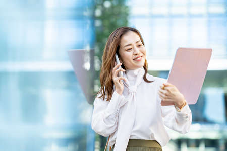 A smiling woman talking on a smartphone outdoorsの写真素材