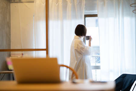 Young woman relaxing by the window with a mug