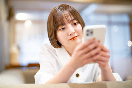 A woman operating a smartphone in the roomの写真素材