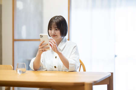 A woman operating a smartphone in the roomの写真素材