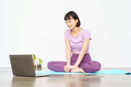 A woman taking an online yoga lesson using a laptopの写真素材