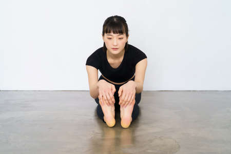 A woman doing a forward bending exercise indoors