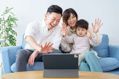 Parents and their little boy waving toward the screen of a tablet PCの写真素材
