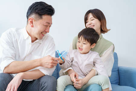 Parents and child brushing teeth on the sofaの写真素材