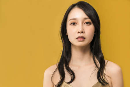 Black-haired woman standing in front of a golden background