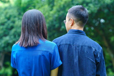 Back view of a young couple taking a walk in a green park