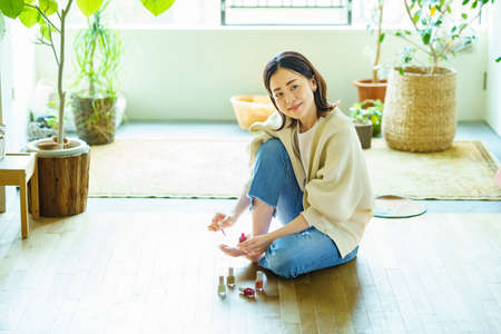 A woman applying gel nails to her toes in the roomの写真素材