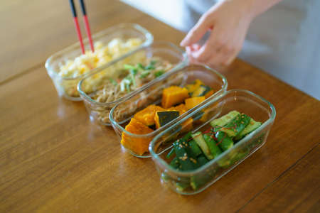 A woman who puts prepared side dishes on a plate on the table