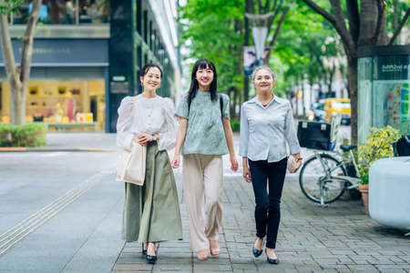 Three women of various generations walking in the city on fine dayの写真素材