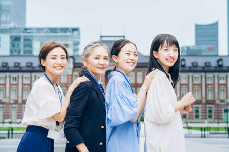 four business women lined up with smiles outdoorsの写真素材