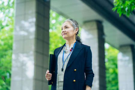 Asian gray-haired business woman standing outdoorsの写真素材