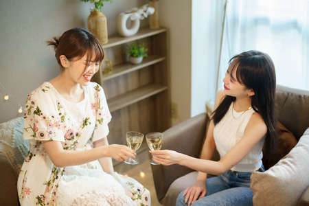 Two women chatting with a glass in their hands indoors