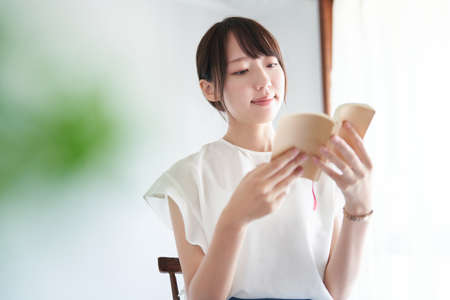 young woman reading a book indoorsの写真素材