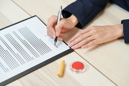 woman in suits signing documents on the deskの写真素材