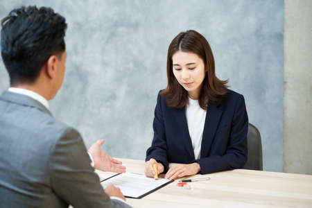 A woman pushing a stamp as a signature on a document in the officeの写真素材