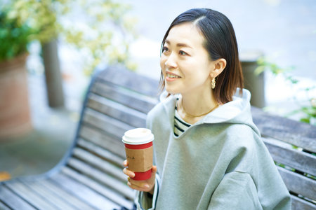 Woman drinking coffee with a relaxed expression outdoors