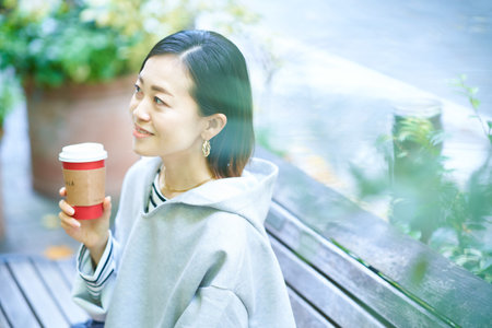Woman drinking coffee with a relaxed expression outdoors