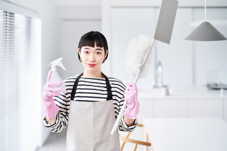 young woman with cleaning tools in the roomの写真素材