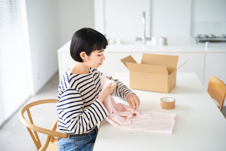 asian young woman holding clothes in the roomの写真素材