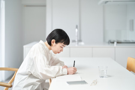 Young woman writing in notebook in the roomの写真素材