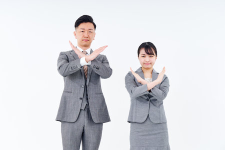 Man and woman in suits who pose for denial and rejection and white backgroundの写真素材