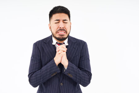 A man in a suit doing a praying pose and white backgroundの写真素材