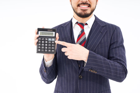 A man in a suit with a calculator and white backgroundの写真素材