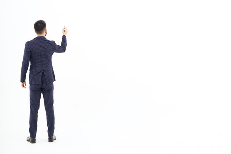 A man in a suit posing to write with a pen and white backgroundの写真素材